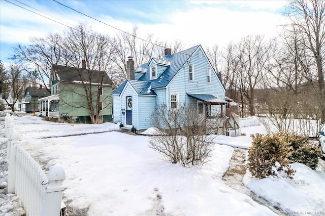 snow covered property featuring fence and a chimney