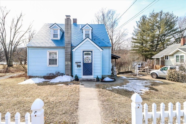 view of front of home with a fenced front yard, a high end roof, and a chimney