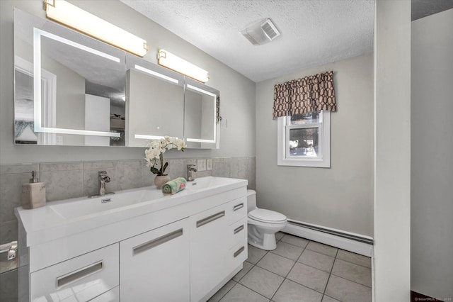 full bathroom with toilet, tile patterned floors, baseboard heating, a textured ceiling, and a sink