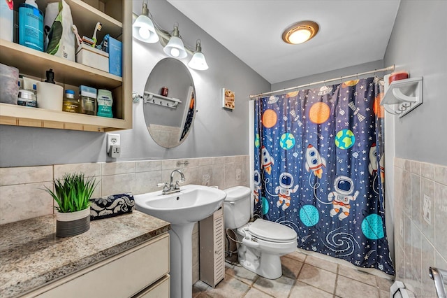 bathroom featuring toilet, wainscoting, a shower with shower curtain, and tile walls