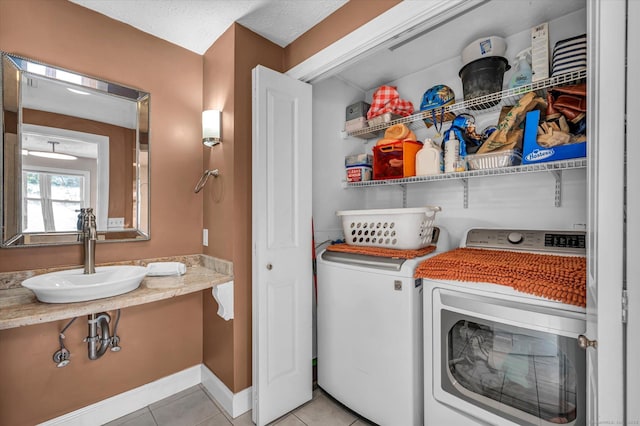 laundry room with washer and clothes dryer, light tile patterned floors, a sink, laundry area, and baseboards