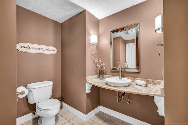 bathroom with toilet, tile patterned flooring, baseboards, and a sink