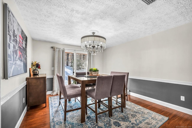 dining room featuring a chandelier, a textured ceiling, baseboards, and wood finished floors