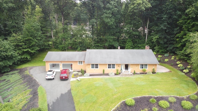 view of front of house with a garage, a front lawn, a chimney, and aphalt driveway