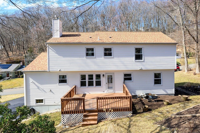 back of property with a shingled roof, a chimney, and a wooden deck