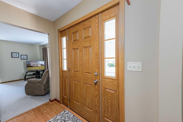 entryway featuring light carpet, plenty of natural light, and baseboards