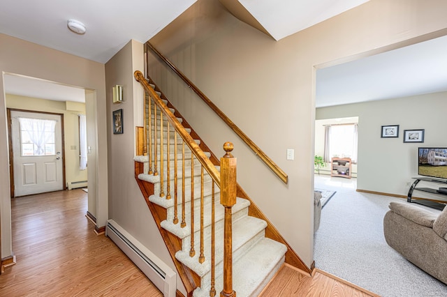 stairway with a baseboard radiator, wood finished floors, and baseboards