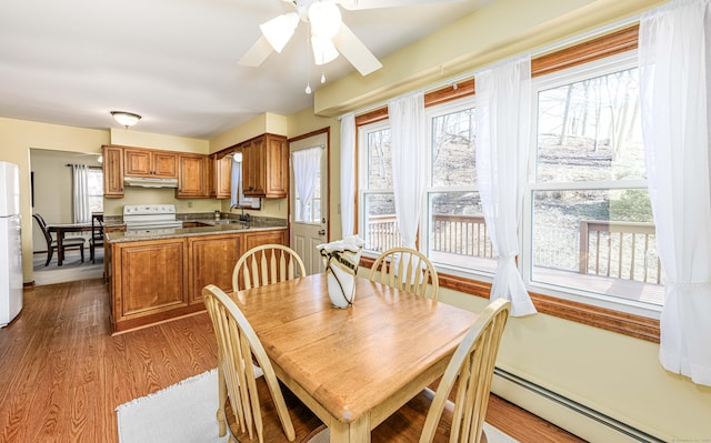 dining space with ceiling fan, baseboard heating, and dark wood-type flooring