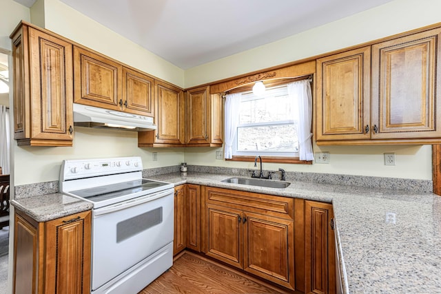 kitchen with white range with electric cooktop, a sink, brown cabinetry, and under cabinet range hood