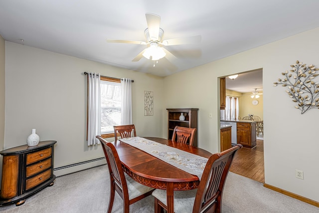 dining area with a baseboard radiator, baseboards, ceiling fan, and light colored carpet