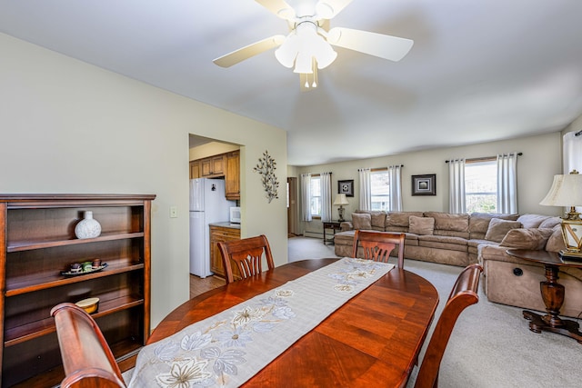 dining space with ceiling fan, baseboard heating, and light colored carpet