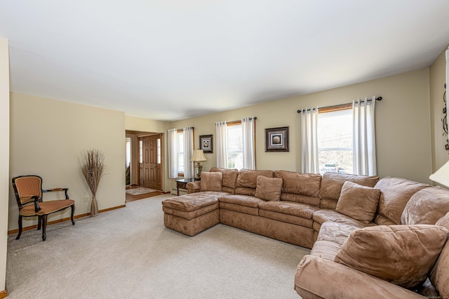 living area featuring light carpet, baseboards, a baseboard heating unit, and a wealth of natural light