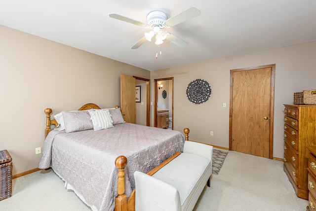 bedroom with light carpet, baseboards, a ceiling fan, and ensuite bathroom