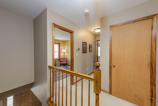 corridor with baseboards, carpet flooring, and an upstairs landing