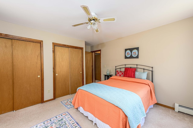 bedroom with baseboards, light colored carpet, ceiling fan, baseboard heating, and two closets