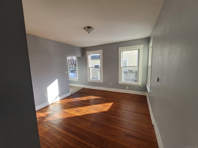 unfurnished room with hardwood / wood-style flooring and baseboards