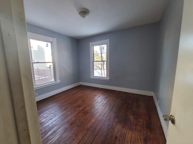 spare room featuring baseboards and dark wood finished floors