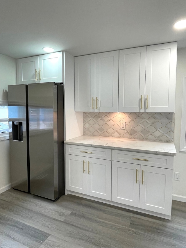 kitchen featuring light wood-style flooring, white cabinetry, backsplash, and stainless steel fridge with ice dispenser