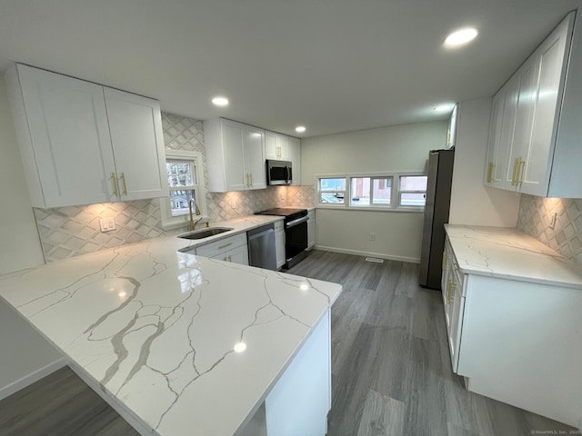 kitchen with stainless steel appliances, recessed lighting, white cabinets, a sink, and light stone countertops