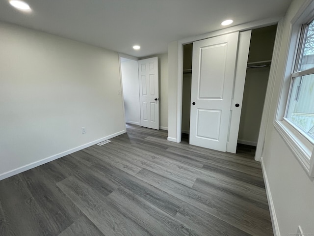 unfurnished bedroom with visible vents, baseboards, dark wood finished floors, multiple windows, and recessed lighting