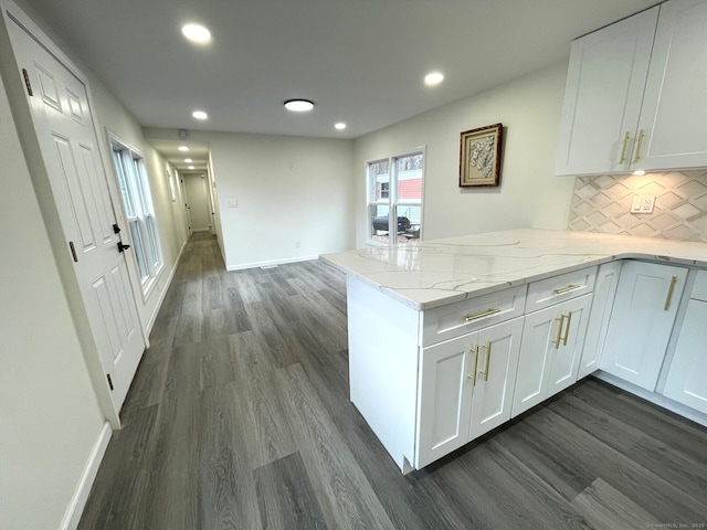 kitchen with a peninsula, white cabinetry, decorative backsplash, and dark wood-type flooring