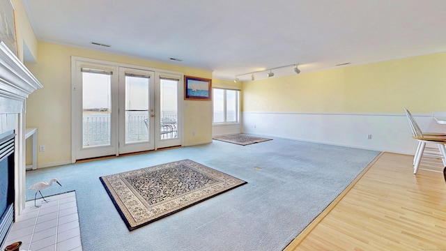 interior space with wood finished floors, a fireplace with flush hearth, baseboards, visible vents, and rail lighting