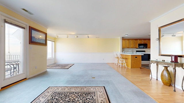 interior space featuring visible vents, brown cabinets, crown molding, black microwave, and range with electric stovetop