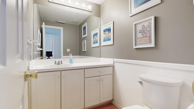 bathroom with toilet, visible vents, and vanity