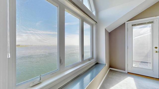 doorway with a healthy amount of sunlight, carpet, baseboards, and vaulted ceiling