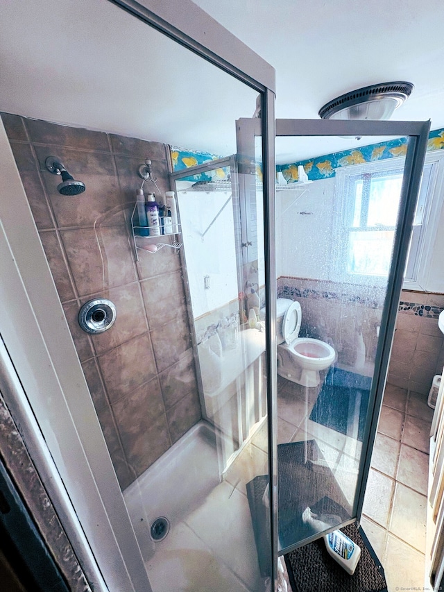 bathroom featuring a stall shower, tile patterned flooring, and toilet