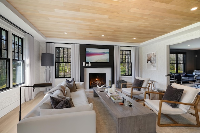living room featuring wood finished floors, plenty of natural light, a lit fireplace, and wooden ceiling