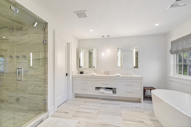 full bath with double vanity, visible vents, a freestanding bath, and a sink