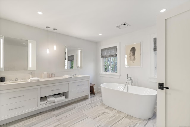 bathroom with visible vents, a freestanding bath, double vanity, and recessed lighting