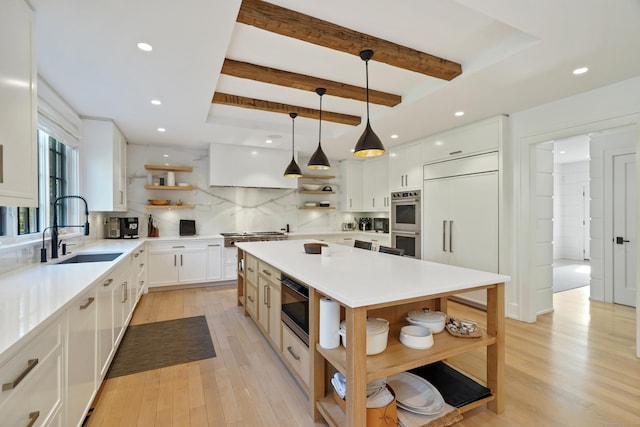 kitchen featuring built in appliances, a center island, open shelves, and a sink