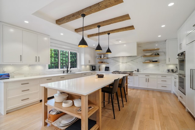 kitchen featuring tasteful backsplash, open shelves, a kitchen bar, and a sink