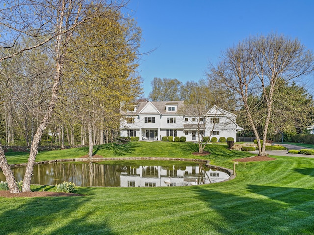 rear view of house featuring a yard and a water view