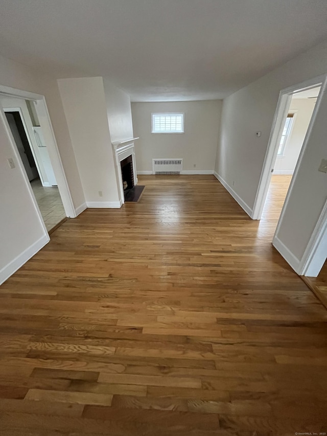 unfurnished living room featuring a fireplace, baseboards, and wood finished floors