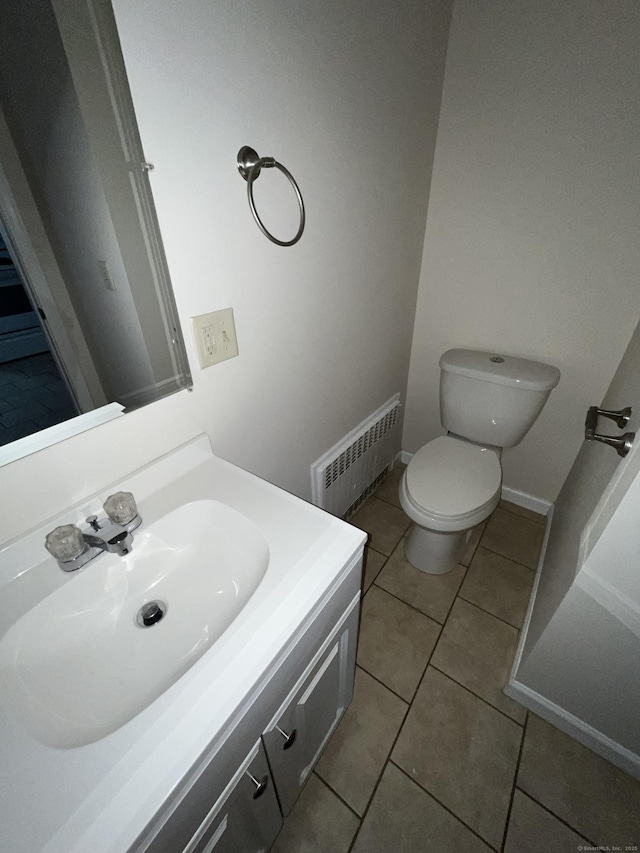 half bath with tile patterned flooring, toilet, vanity, visible vents, and baseboards