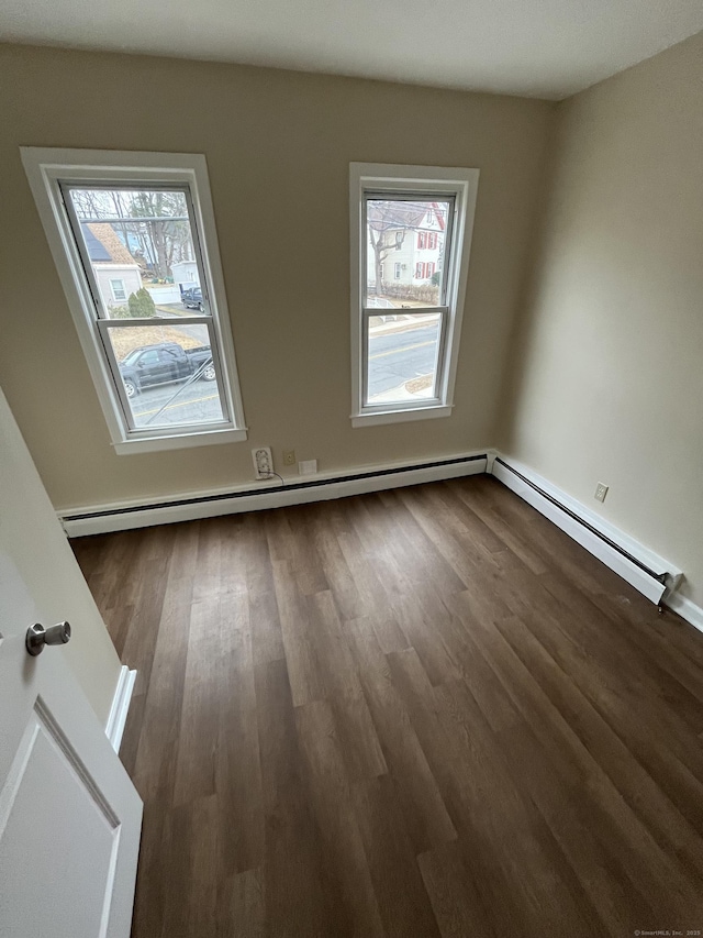 empty room with plenty of natural light, a baseboard heating unit, and dark wood-type flooring