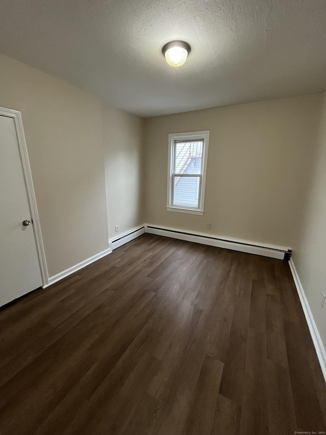 spare room featuring dark wood-style floors, a textured ceiling, a baseboard radiator, and baseboards