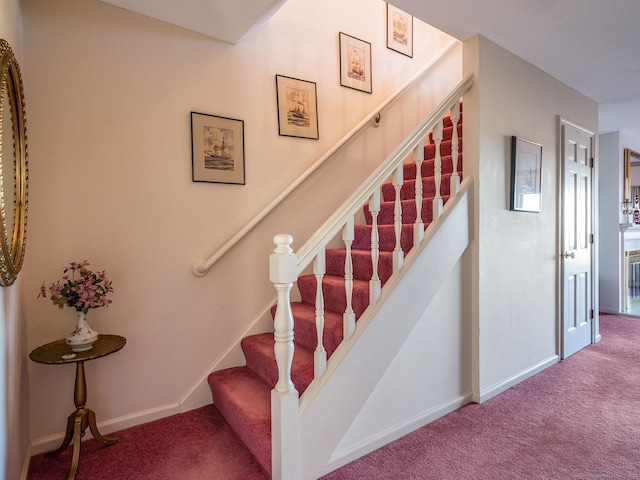 stairway with baseboards and carpet floors