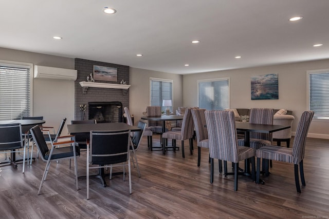 dining space with dark wood finished floors, an AC wall unit, a brick fireplace, and recessed lighting