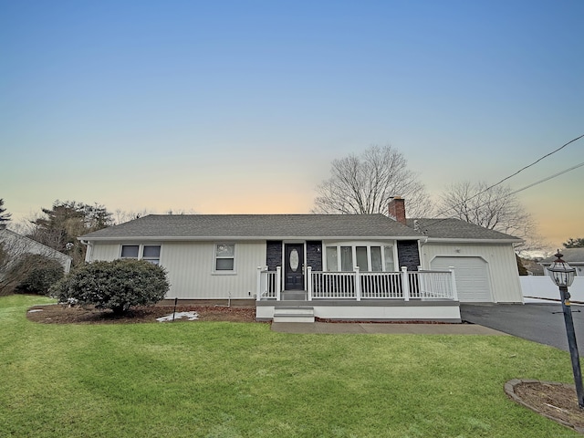 ranch-style home with a chimney, a front lawn, an attached garage, and driveway