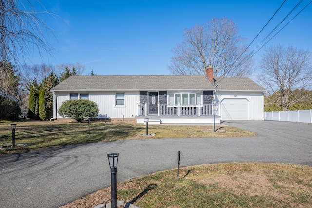 ranch-style house with a front lawn, aphalt driveway, a porch, a chimney, and a garage