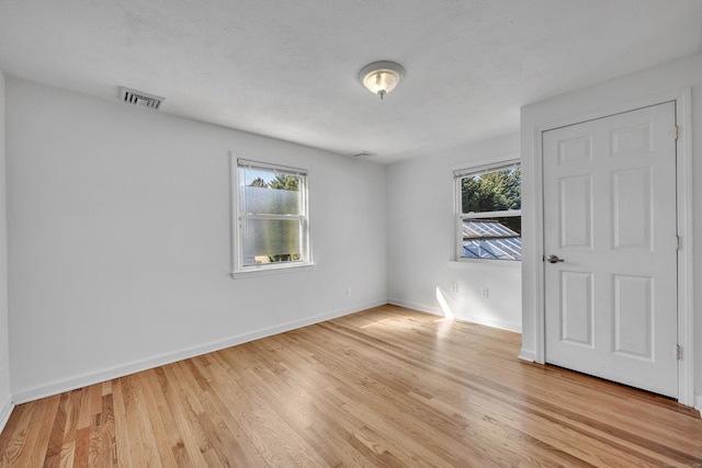 empty room with visible vents, plenty of natural light, light wood-style floors, and baseboards