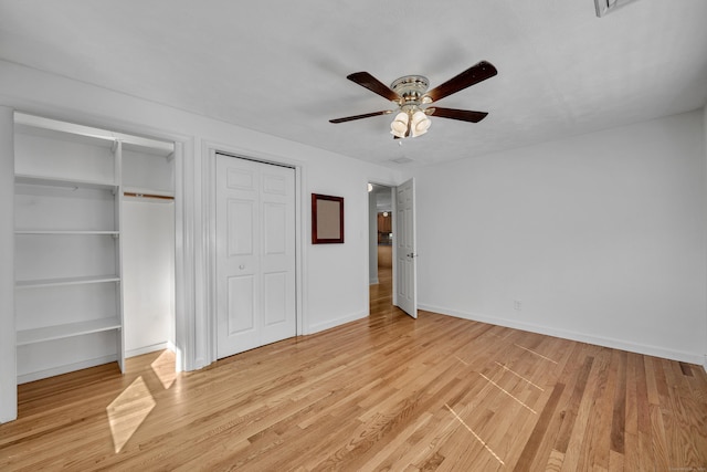 unfurnished bedroom featuring light wood-style flooring, a ceiling fan, baseboards, and two closets