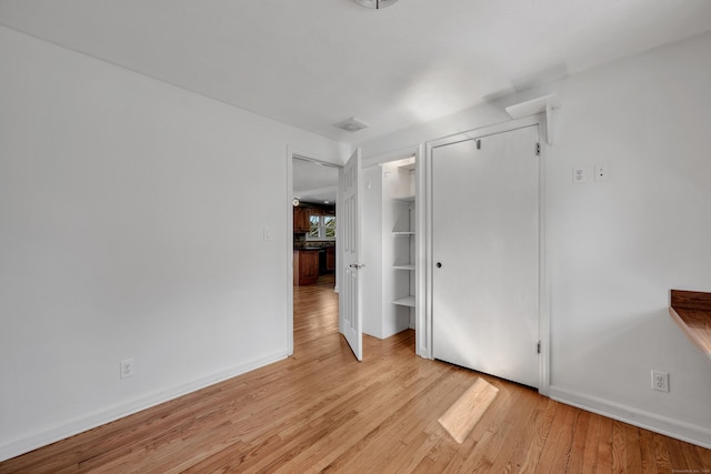 unfurnished bedroom featuring a closet, baseboards, and light wood-style floors