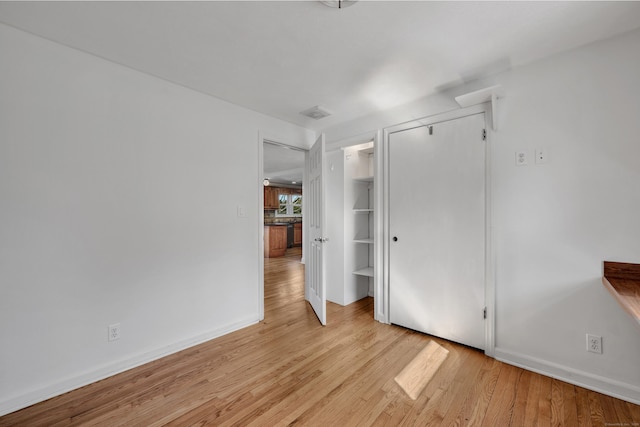 unfurnished bedroom featuring a closet, baseboards, and light wood-style flooring