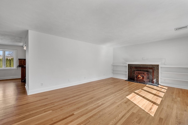 unfurnished living room with visible vents, baseboards, built in features, light wood-style flooring, and a fireplace