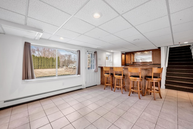 bar with a paneled ceiling, a baseboard heating unit, bar area, and stairway